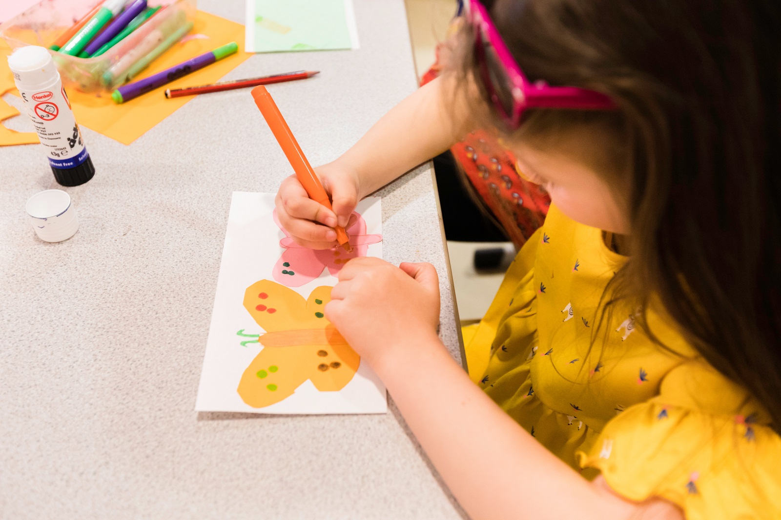 © Christopher Ison / Pallant House Gallery A young girl decorstes a piece of paper with a yellow butterfly design