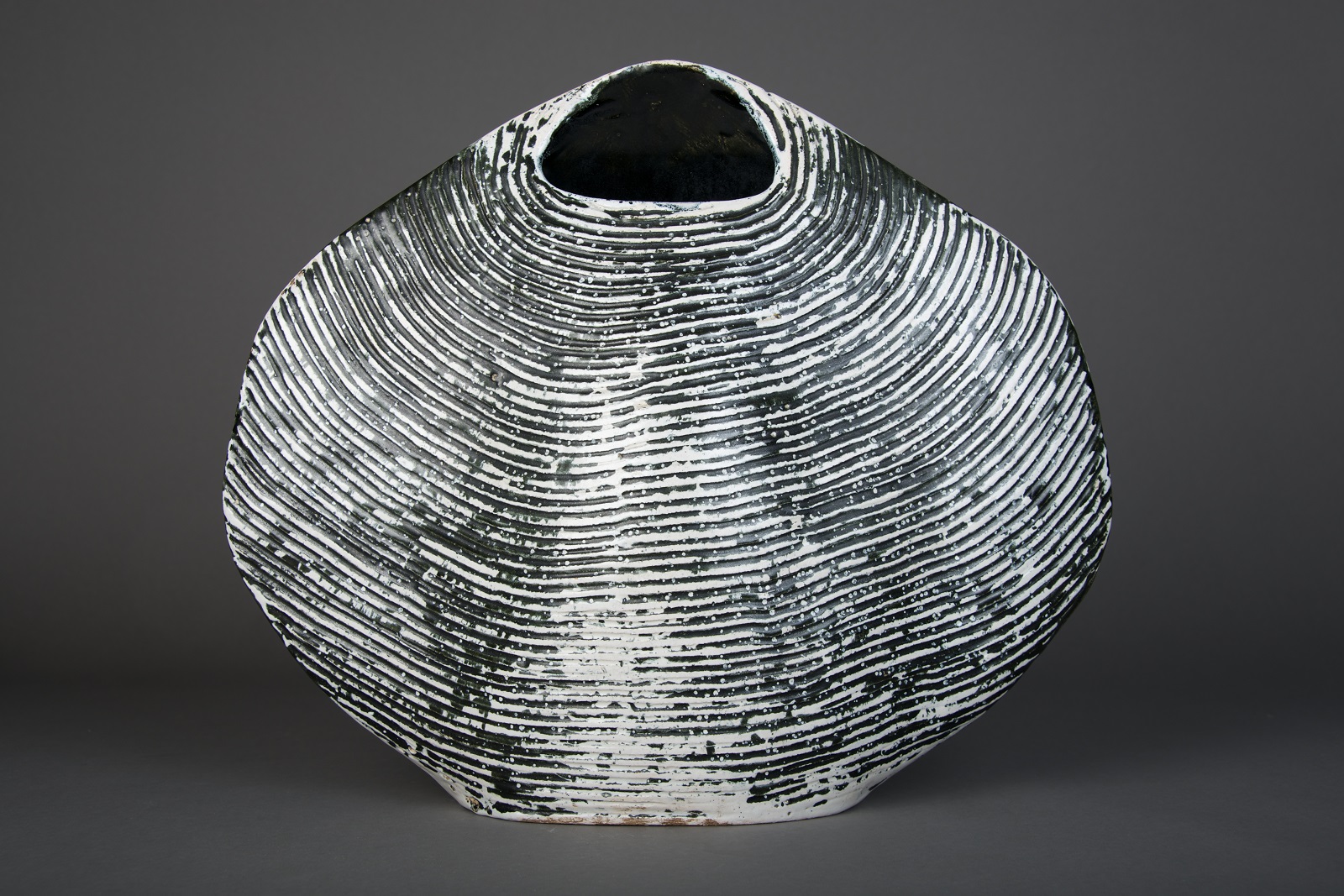 James Tower, Shell Vase (1958) Large cockle shell shape vase with small opening at the top modelled in creamy grey. The ridges in the clap look black.