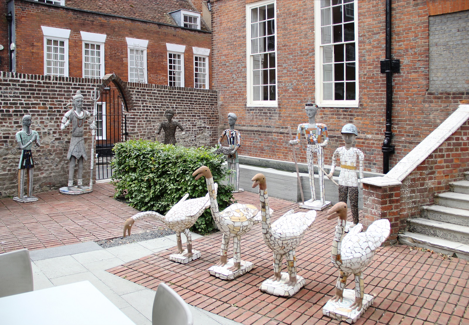 Nek Chand at Pallant House Gallery (2015) A set of four swan sculptures stand in a row in front a row os sculptures of human figures. All the sculptures are made from concrete and discarded pottery fragments
