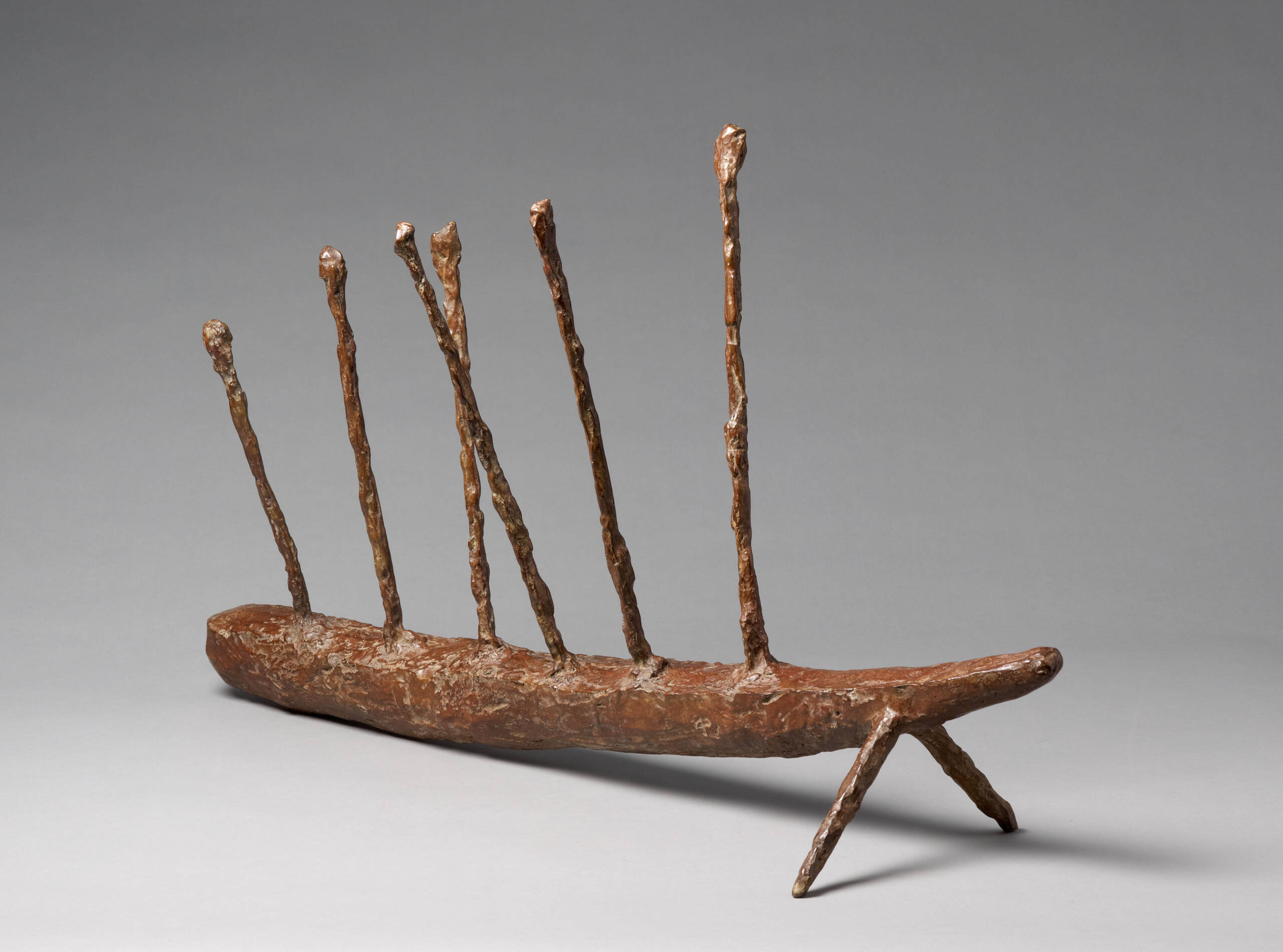 Bronze sculpture of an insect with two front legs a long cylindrical body and six spikes along back